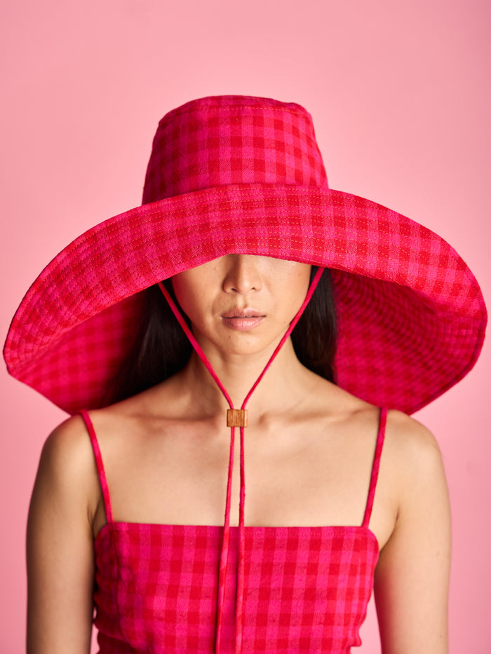 The Lucie Marquis 'Dylan Sunhat' is a wide brimmed sun hat with heavy topstitching and a wooden block cord end. Inspired by the iconic spirit of Bob Dylan and the bold essence of Georgia O'Keeffe, the sun hat embodies timeless style with a subtle nod to the 70s and a touch of cowboy charm. Perfect for shielding from the sun, it's the ideal accessory for your travel adventures.