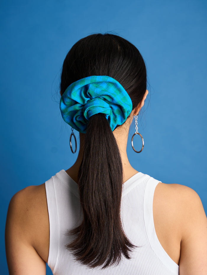 The Lucie Marquis 'Susie Scrunchie' is a stylish oversized hair scrunchie made from leftover fabric scraps. The scrunchie is 7cm wide and designed to wrap around twice. It features a brand label stitched flat on one side. The scrunchie effortlessly elevates any outfit. A great travel accessory, sustainably made.