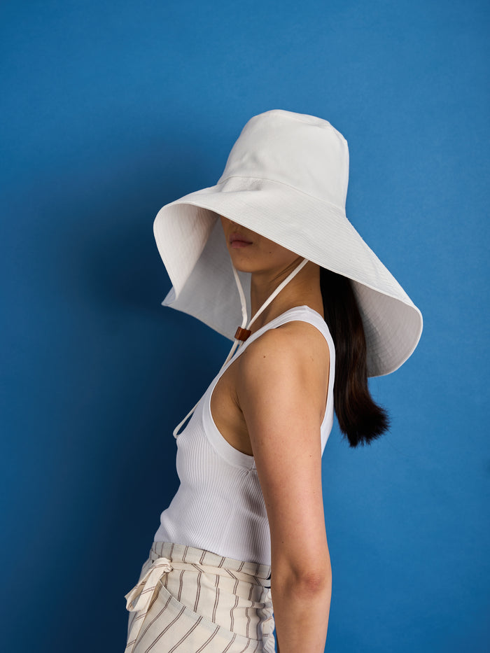 Introducing the 'Dylan Sunhat', where the iconic spirit of Bob Dylan meets the bold essence of Georgia O'Keeffe. This wide brimmed sun hat is the epitome of timeless style, with a subtle nod to the 70s and a touch of cowboy allure. Made from high-quality cotton twill, the Dylan Sunhat features heavy topstitching and a wooden block cord end – it's the perfect accessory to shield you from the sun.
