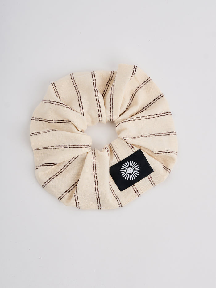 The Lucie Marquis 'Susie Scrunchie' is a stylish oversized hair scrunchie made from leftover fabric scraps. The scrunchie is 7cm wide and designed to wrap around twice. It features a brand label stitched flat on one side. The scrunchie effortlessly elevates any outfit. A great travel accessory, sustainably made.