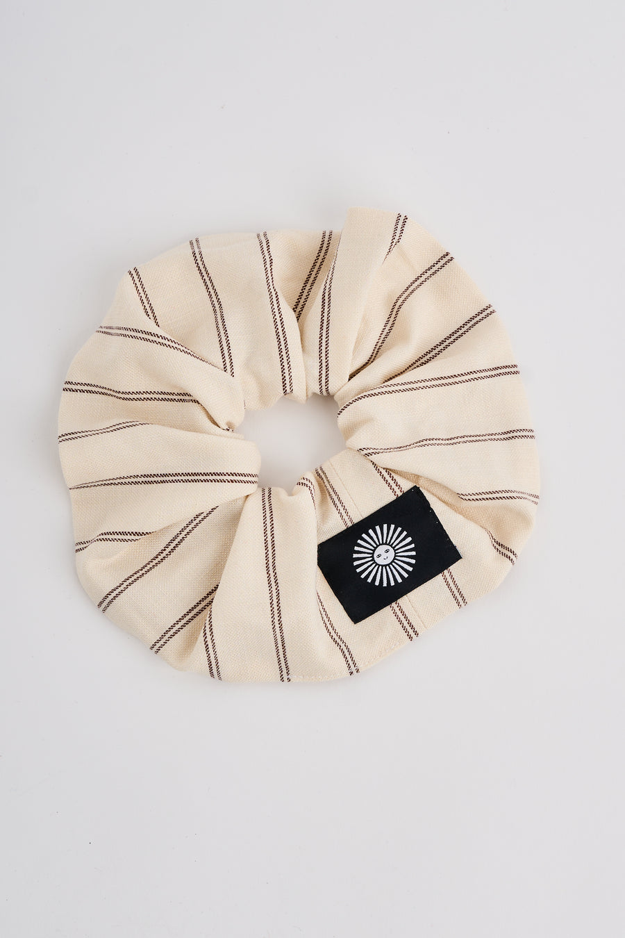 The Lucie Marquis 'Susie Scrunchie' is a stylish oversized hair scrunchie made from leftover fabric scraps. The scrunchie is 7cm wide and designed to wrap around twice. It features a brand label stitched flat on one side. The scrunchie effortlessly elevates any outfit. A great travel accessory, sustainably made.
